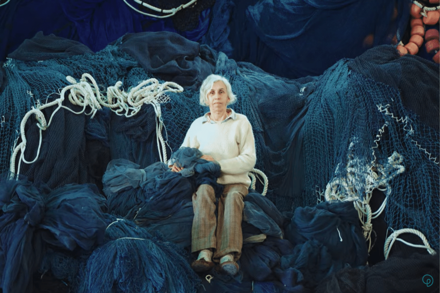 Nara Guichon sentada em várias redes de pesca.